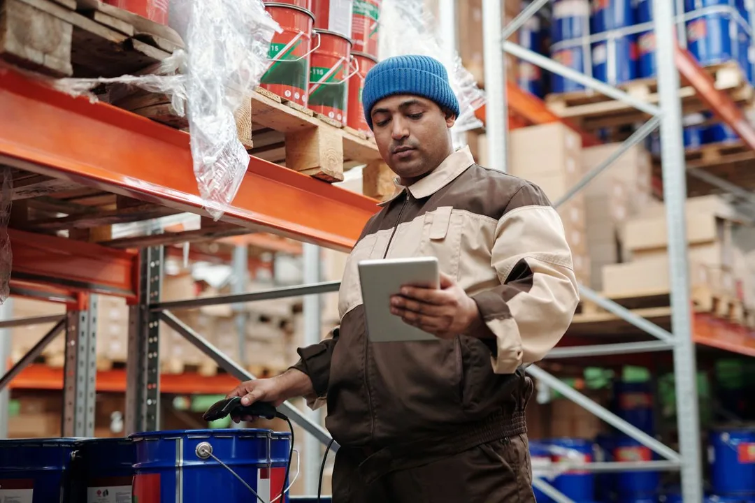 Storekeeper checking stock on a tablet between warehouse racks