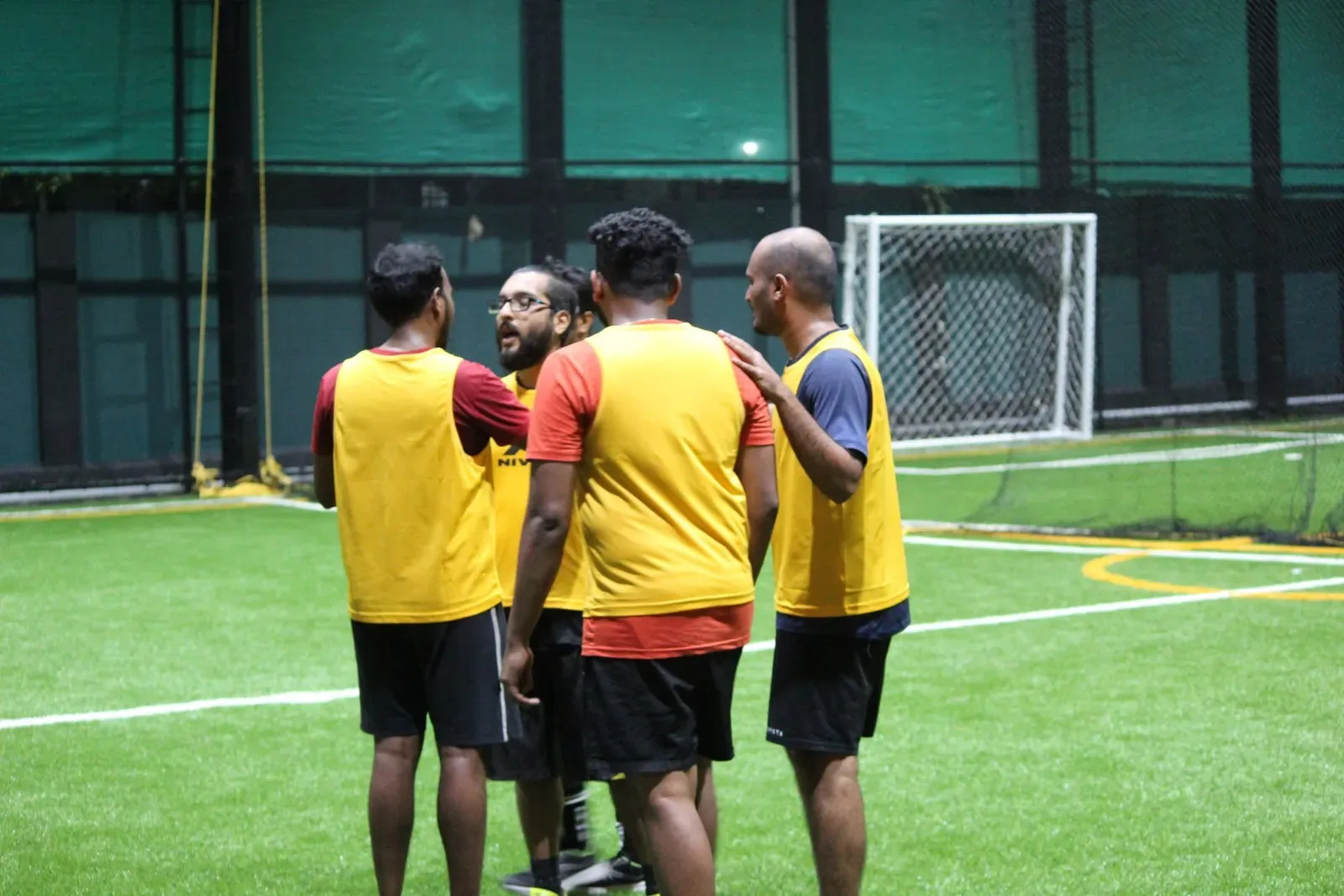 Players in bibs talking on the pitch before a match