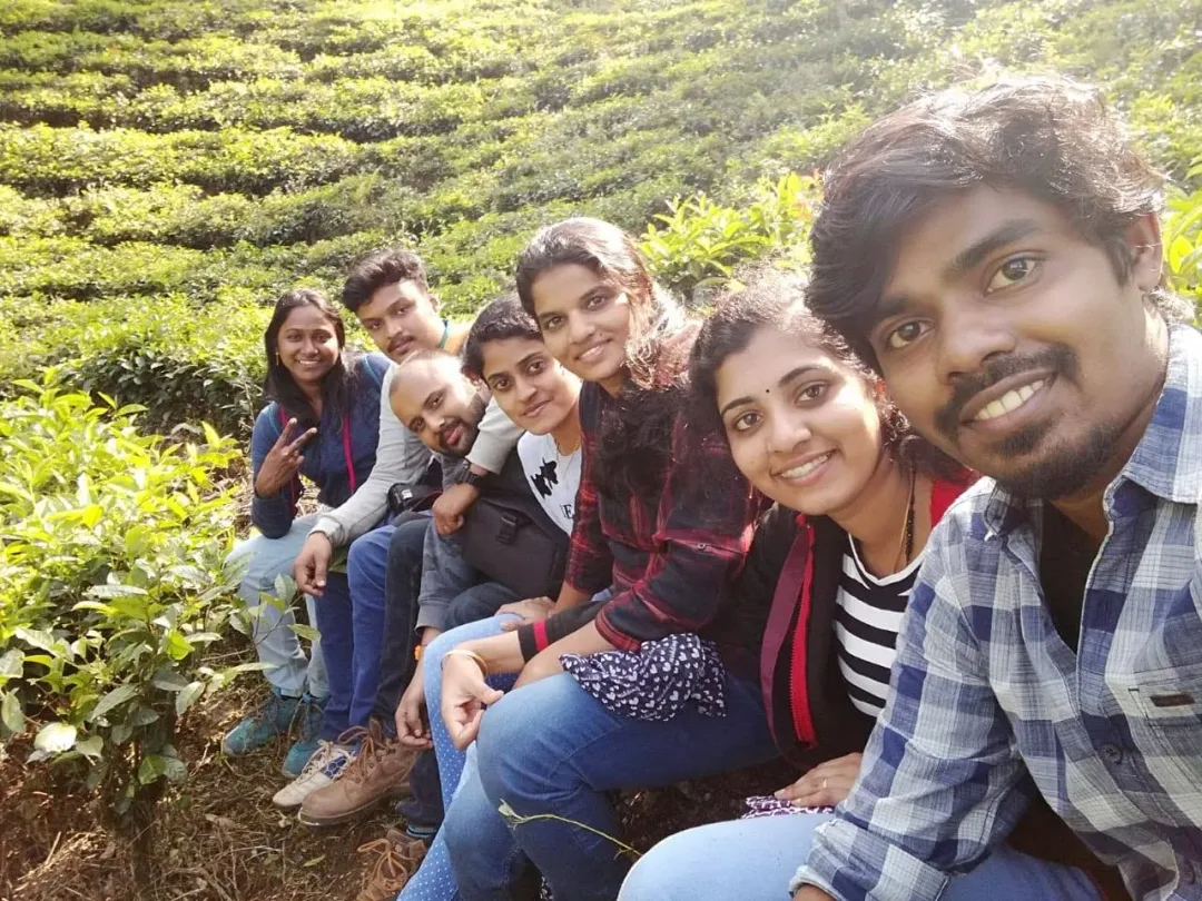 A group of the Acube team sitting on a tea estate in Munnar